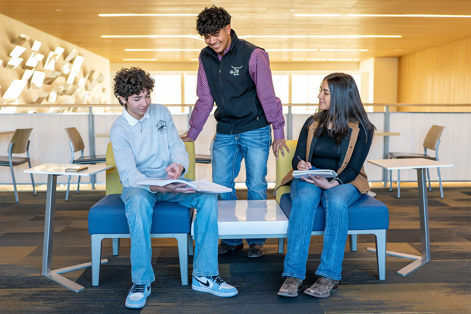 A group of three students reviewing information in textbook.